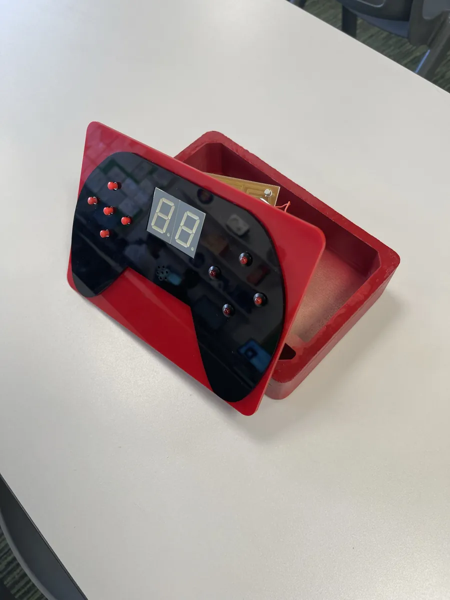 Finished reaction-time game: a red enclosure with a black controller-shaped faceplate, red LEDs and a two-digit display
